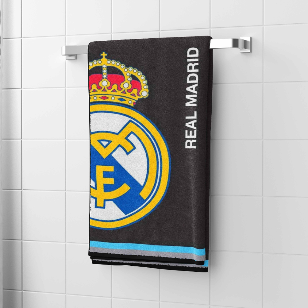 Ręcznik łazienkowy „Real Madrid black towel“. Ręczniki, 70x140 cm. Czarny ręcznik o tematyce klubu piłkarskiego „real madryt”, zawieszony w łazience, z wyraźnie widocznym logo klubu oraz napisem.